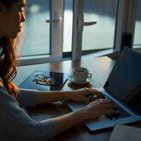 Ein Frau am Laptop mit einer Tasse Kaffee auf dem Tisch führt in bis zu sechs Schritten kann eine Online Scheidung bei der Anwältin Gabriela Althoff aus Berlin durch